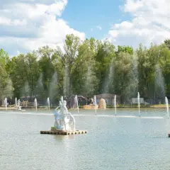 Park mitologii na wodzie z rzeźbami bogów i bogiń, otoczony zielenią i fontannami.