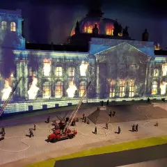 Miniaturowy pożar Reichstagu w **little big city Berlin**. Strażacy walczą z płomieniami, a dym unosi się w mroku.