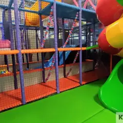 Kolorowy plac zabaw w parku rozrywki Koszalin z rurami, zjeżdżalniami i basenem z kulkami.