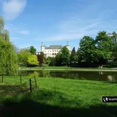 Zamek w Książu, jedna z największych atrakcji Dolnego Śląska, otoczony zielenią i stawem.
