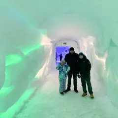 Rodzina w lodowym tunelu, gdzieś w okolicy wioski Mikołaja w Finlandii. Ściany lśnią zielonym światłem.