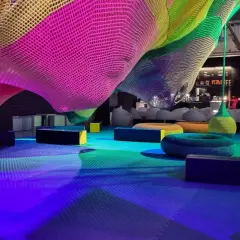 Kolorowa, pleciona konstrukcja w Funzeum Gliwice, z miękkimi siedziskami i podłogą w odcieniach niebieskiego i zielonego.