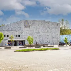 Fasada budynku z motywem labiryntu, symbolizująca park nauki i ewolucji człowieka. Obok monumentalny łuk.