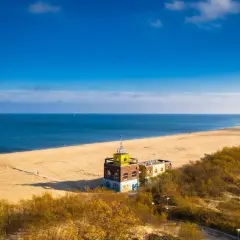 Gdańsk plaża z charakterystycznym budynkiem i piaszczystym wybrzeżem. Błękitne morze i niebo tworzą spokojny krajobraz.