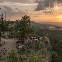 Widok z tarasu restauracji na malowniczą kotlinę kłodzką o zachodzie słońca.