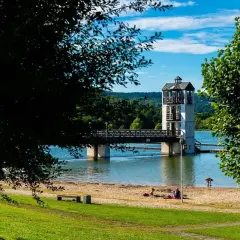 Stara Morawa zalew z wieżą widokową i mostem. Na piaszczystej plaży odpoczywają ludzie.