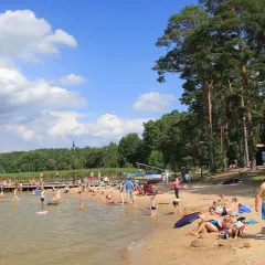 Słoneczna augustowska plaża tętni życiem. Ludzie kąpią się, opalają i relaksują na piasku, ciesząc się letnim dniem nad jeziorem.
