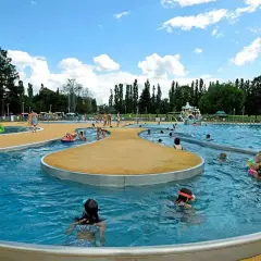 Rodzinna zabawa w moczydło park wodny. Dzieci pluskają się w wodzie, ślizgają na zjeżdżalniach, a dorośli odpoczywają na brzegu.