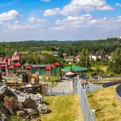Kolorowy zamek i karuzela w **Ogrodzieńcu park rozrywki**. Dzieci bawią się na zjeżdżalni i placu zabaw.