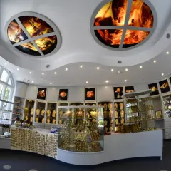 Wnętrze muzeum bursztynu Kołobrzeg. W gablotach błyszczą złote ozdoby, a na suficie widnieją okrągłe iluminacje z bursztynem.
