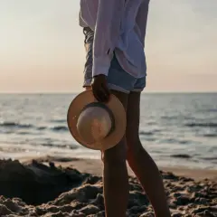 Spacer po plaży w Kołobrzegu. Słońce zachodzi nad morzem, a w dłoni trzymam słomkowy kapelusz.