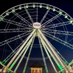 Ogromny diabelski młyn Energylandia lśni zielonym światłem na tle nocnego nieba.