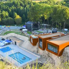 Ulinapark tętni życiem: koncert na scenie, baseny, punkty gastronomiczne i nowoczesne budynki na skale.