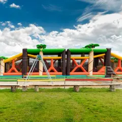 Kolorowy park rozrywki zachodniopomorskie z dmuchanymi zjeżdżalniami i przeszkodami w kształcie dżungli.
