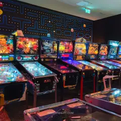 Rząd automatów do gry w stylu retro, w tym maszyny Baywatch i Terminator, tworzy klimat prawdziwego **arcade museum**.