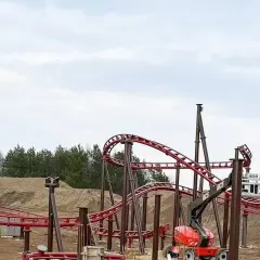 Budowa **Hosso Park Rozrywki** trwa. Czerwone tory kolejki górskiej wznoszą się nad placem budowy, gdzie pracują dźwigi i koparki.