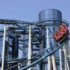 Wesoła kolejka górska z pasażerami wjeżdża na szczyt przy nowoczesnych budynkach w Europa Park Niemcy.