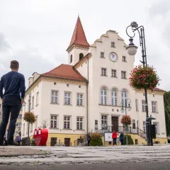 Mężczyzna patrzy na ratusz w Trzebnicy, jedno z głównych atrakcji miasta. W tle widać zegar i czerwone serca.
