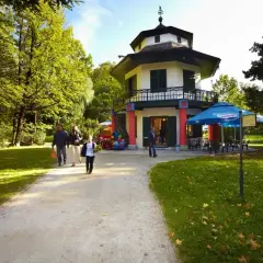 Rodzina spaceruje po malowniczym parku w Żywcu, w tle widać chiński pawilon i kawiarnię.