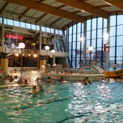 Ludzie pluskają się w basenie Warszawianka. W tle widać zjeżdżalnię i restaurację Bostonport.