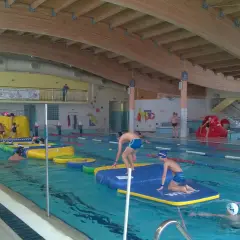 Dzieci bawią się na dmuchanych przeszkodach w krytej pływalni Oceanik. Radosne pluskanie i wodne szaleństwo.