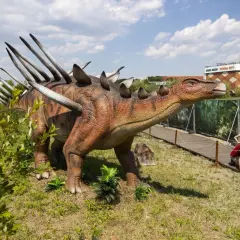 Model dinozaura w parku dinozaurów Kraków. Dzieci oglądają stegozaura.