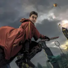 Harry Potter na miotle, w czerwonym szacie, ściga Złoty Znicz podczas meczu quidditcha. To scena z filmu "Harry Potter i Zakazana Podróż".