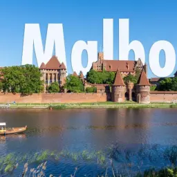 Majestatyczny zamek w Malborku, jedna z największych atrakcji Polski, widziany od strony rzeki Nogat. Stateczek wycieczkowy płynie po wodzie.