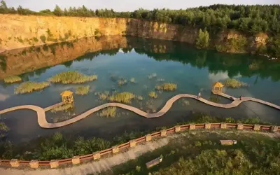 Malowniczy park Gródek z drewnianymi kładkami wijącymi się pośród turkusowej wody i wysepek z trzcinami.