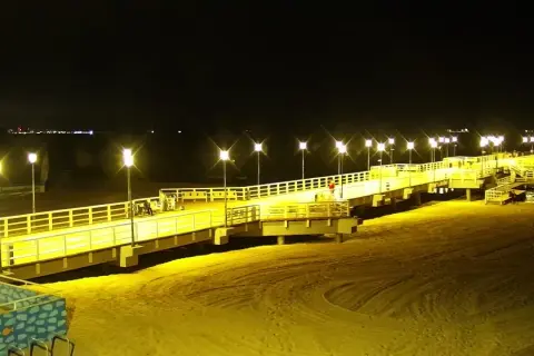 Nocne Jelitkowo: oświetlony molo, plaża i morze. Atrakcje turystyczne w blasku latarni.