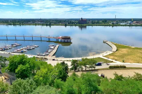 Płock co zobaczyć: malownicza marina z żaglówkami, nowoczesny deptak nad Wisłą i industrialne krajobrazy w tle.