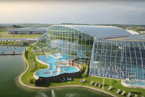 Nowoczesny park wodny pod Warszawą z basenami i palmami pod szklaną kopułą.