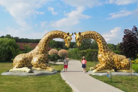 Dzieci pozują między gigantycznymi żyrafami w parku rozrywki Wielkopolska.