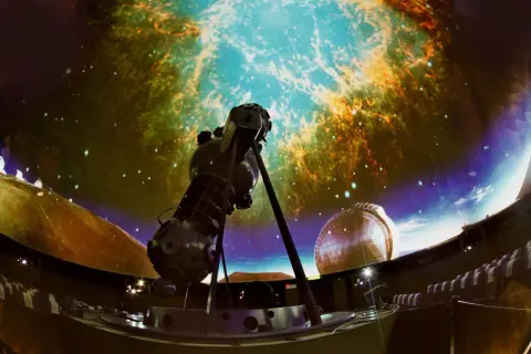 Wielki projektor gwiazd w centrum, otoczony siedzeniami, tworzy magiczne planetarium dla dzieci.
