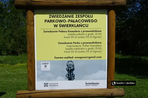 Tablica informacyjna o zwiedzaniu zespołu parkowo-pałacowego w Świerklańcu. Informacje o zwiedzaniu pałacu i parku z przewodnikiem, kosztach i godzinach.