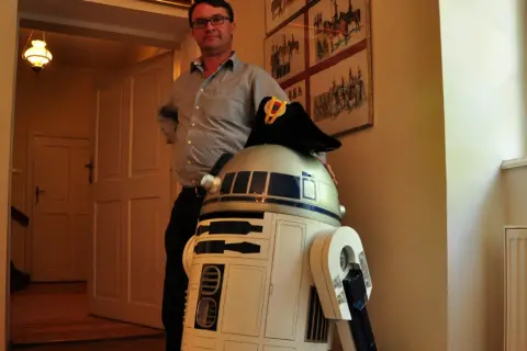 W muzeum Star Wars R2-D2 w wojskowym kapeluszu pozuje z mężczyzną.