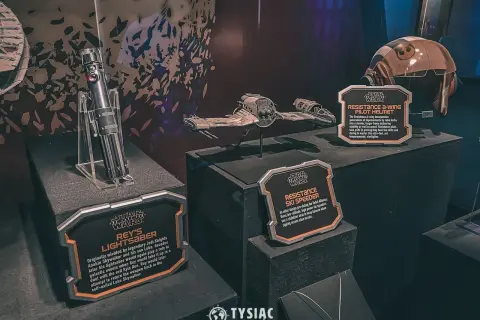 Miecz świetlny Rey, hełm pilota A-winga i pojazd Resistance Ski Speeder z wystawy Star Wars Galaxy's Edge.