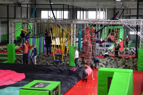 Wesoła zabawa w parku rozrywki Flysky! Dzieci skaczą, wspinają się i pokonują przeszkody na trampolinach i w basenie z gąbkami.