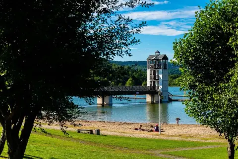 Stara Morawa zalew z wieżą widokową i mostem. Na piaszczystej plaży odpoczywają ludzie.
