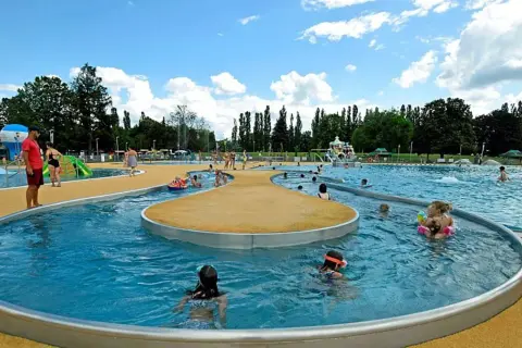 Rodzinna zabawa w moczydło park wodny. Dzieci pluskają się w wodzie, ślizgają na zjeżdżalniach, a dorośli odpoczywają na brzegu.