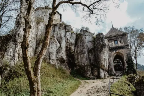 Ojcowski Park Narodowy atrakcje: ruiny zamku na skale, kamienna wieża bramna i ścieżka wśród zieleni.