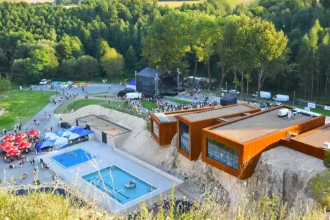 Ulinapark tętni życiem: koncert na scenie, baseny, punkty gastronomiczne i nowoczesne budynki na skale.