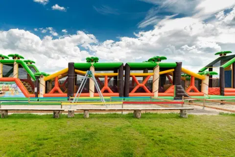 Kolorowy park rozrywki zachodniopomorskie z dmuchanymi zjeżdżalniami i przeszkodami w kształcie dżungli.