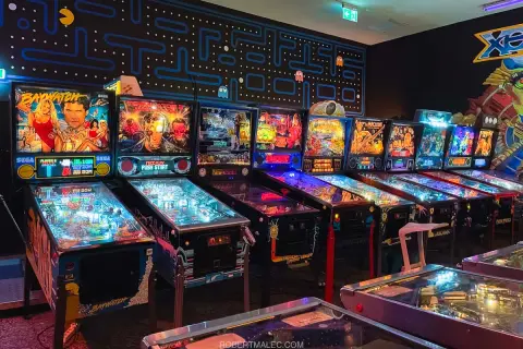 Rząd automatów do gry w stylu retro, w tym maszyny Baywatch i Terminator, tworzy klimat prawdziwego **arcade museum**.