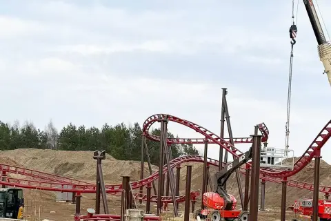 Budowa **Hosso Park Rozrywki** trwa. Czerwone tory kolejki górskiej wznoszą się nad placem budowy, gdzie pracują dźwigi i koparki.