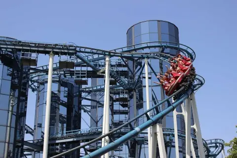 Wesoła kolejka górska z pasażerami wjeżdża na szczyt przy nowoczesnych budynkach w Europa Park Niemcy.