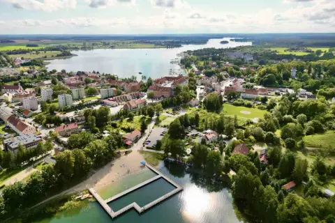 Malownicze miasteczko nad jeziorem, z plażą i basenem kąpielowym. Ryn oferuje wiele atrakcji, idealne miejsce na wypoczynek.