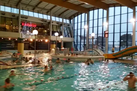Ludzie pluskają się w basenie Warszawianka. W tle widać zjeżdżalnię i restaurację Bostonport.
