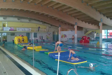 Dzieci bawią się na dmuchanych przeszkodach w krytej pływalni Oceanik. Radosne pluskanie i wodne szaleństwo.