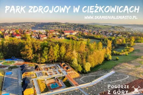 Park Zdrojowy w Ciężkowicach oferuje liczne atrakcje: plac zabaw, basen, sauny i ścieżki spacerowe. Widok z góry na malownicze Pogórze.